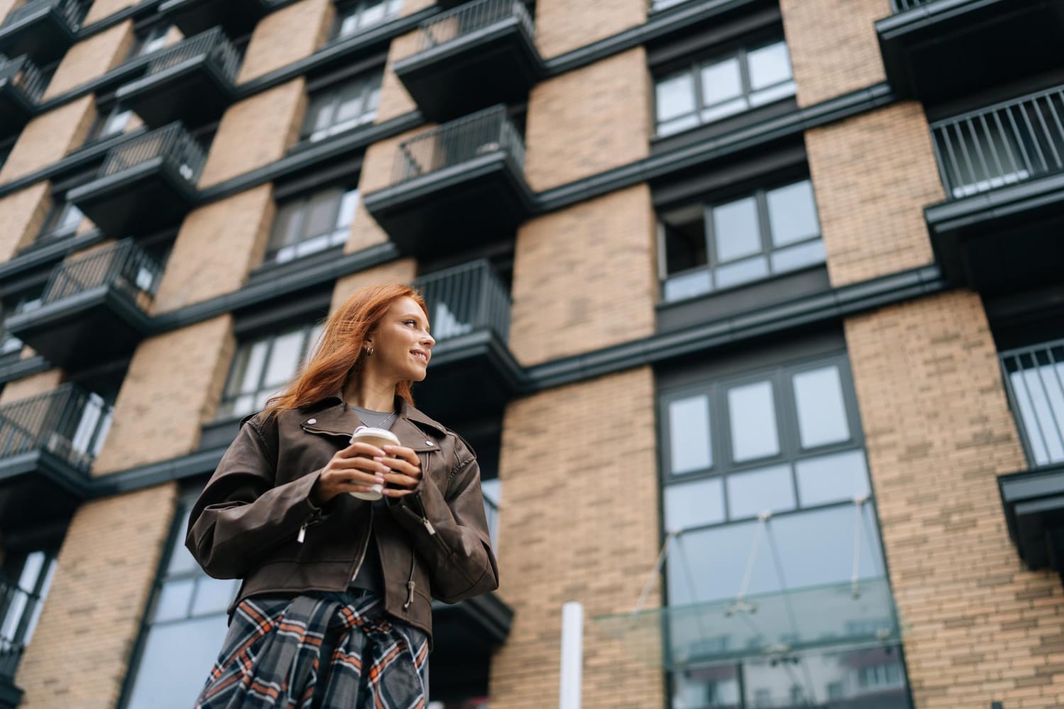 A woman using the Emma app on her phone, looking thoughtfully in London and planning to buy a house in 2025.